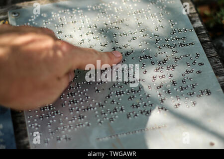 Un dettaglio del testo in alfabeto Braille. Il dettaglio delle informazioni di un segno. Il dito è la lettura di adesso. Foto Stock