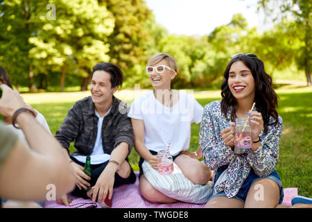 Happy amici con bevande al picnic nel parco di estate Foto Stock