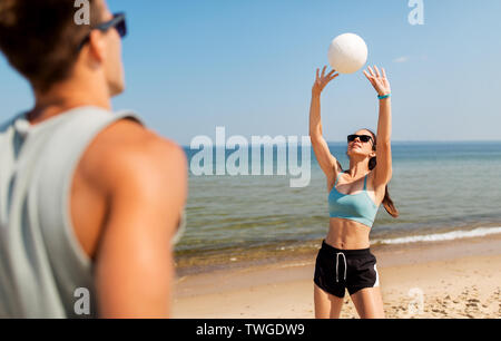 Coppia felice giocando a pallavolo sulla spiaggia di estate Foto Stock