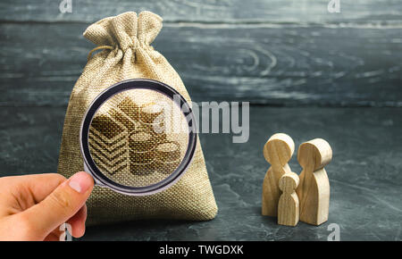 Miniatura in legno figurine famiglia stare vicino a un sacco di denaro. Il concetto di risparmio. Pianificazione del bilancio. Distribuzione degli utili. Gestione finanziaria. Accu Foto Stock