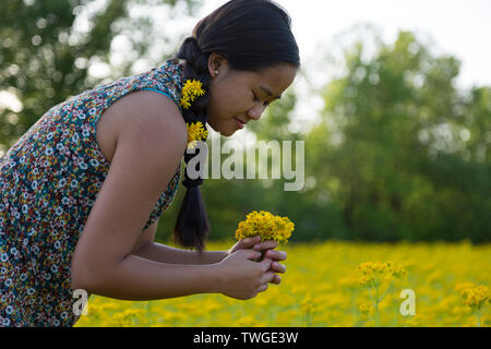 Una bella ragazza adolescente con fiori nei capelli fa un mazzo di fiori in Fort Wayne, Indiana, Stati Uniti d'America. Foto Stock