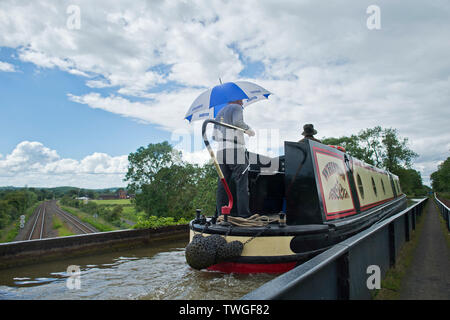 I vacanzieri riparo dalla pioggia su una croce narrowboat l acquedotto Edstone durante una calda e piacevole giornata nel Warwickshire, Regno Unito. Il 20 giugno 2019. Foto Stock