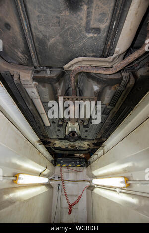 La Toyota Prius, rubato il convertitore catalitico. Vittima di un furto di sistema di scarico. Meccanica pozzetto di ispezione, che mostra la posizione dei componenti danneggiati. Foto Stock