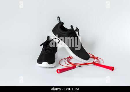 Sport nero scarpe con suola bianca e rossa salto con la corda isolato su sfondo bianco. Concetto di fitness e uno stile di vita sano Foto Stock