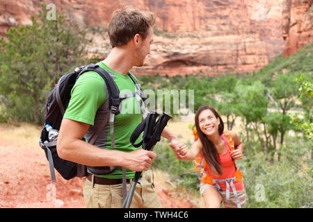 Mano - escursionismo donna come ottenere aiuto su escursione sorridendo felice. Uno stile di vita attivo escursionista giovane in viaggio. Bella sorridente razza mista asiatico femmina caucasica nel Parco Nazionale di Zion, Utah, Stati Uniti d'America. Foto Stock