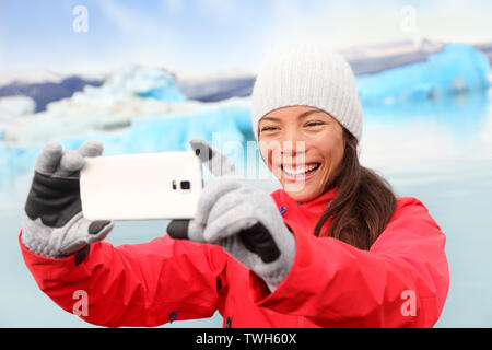 Donna prendendo selfie autoritratto foto di Jokulsarlon laguna glaciale / lago glaciale in Islanda. Felici turisti in viaggio utilizzando smartphone gode di splendida natura Islandese paesaggio con Vatnajokull Foto Stock