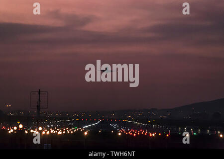 Aerei per il trasporto di passeggeri in partenza dall'Aeroporto Internazionale di Città del Capo al tramonto con la pista di atterraggio chiaramente illuminato. Foto Stock