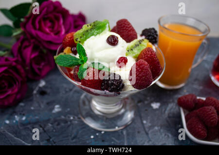 Succo in un bicchiere, gelato alla crema con frutti di bosco e menta sfondo. Rose Foto Stock