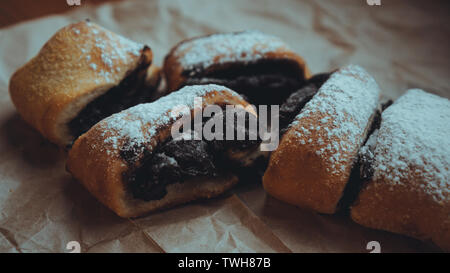 Pane appena sfornato panini al cioccolato con una deliziosa riempimento, spolverati con zucchero a velo. Contro lo sfondo di colore marrone carta craft Foto Stock