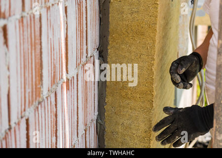 Lavoratore di installare pannelli in lana di roccia sulla parete di facciata Foto Stock