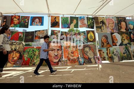 (190620) -- AMMAN, 20 giugno 2019 (Xinhua) -- la gente a piedi passato opere di pittura da rifugiati presso l'UNHCR estivo di bazar in Amman, Giordania, il 20 giugno 2019. In occasione della Giornata Mondiale del Rifugiato, l UNHCR ha esortato la comunità internazionale giovedì di intensificare il sostegno alla Giordania per la continuazione dei servizi per i rifugiati. (Xinhua/Mohammad Abu Ghosh) Foto Stock