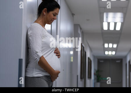 Donna incinta di toccare la sua pancia in corridoio Foto Stock