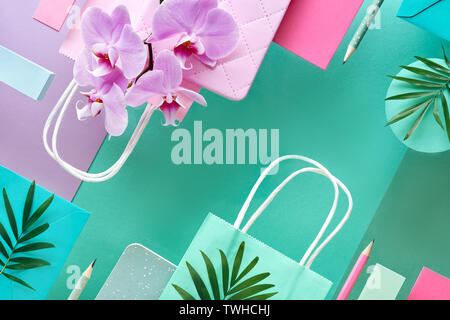 Carta floral background in menta e colori pastello. Fiori di orchidea su sfondo geometrico con le schede di carta, foglie e matite Foto Stock