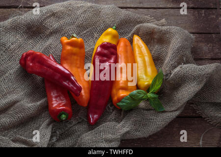 Rosso, giallo e peperoni arancione su sfondo di lino, copia dello spazio. Foto Stock