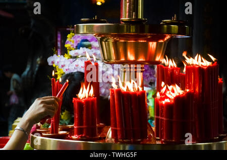 Donna luci a mano candele rosse nel tempio buddista, Taiwan e Cina. Concezione religiosa, spiritualità, fede, Dio. Simbolo di Buddha Asia religione asiatica. Foto Stock