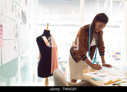 Moda femminile designer disegno schizzo sul tavolo in un ufficio moderno Foto Stock