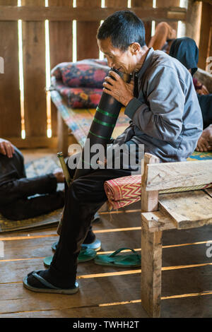 Uomo di fumare oppio dal tradizionale tubo di tabacco in akha Pixor villaggio vicino Phongsali, Laos. Foto Stock