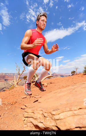 Atleta fitness bench salto squat jumping in natura paesaggio. Forza di formazione maschio adatta a lavorare fuori esercizio all'aperto in estate a fare il salto sulla roccia. Foto Stock