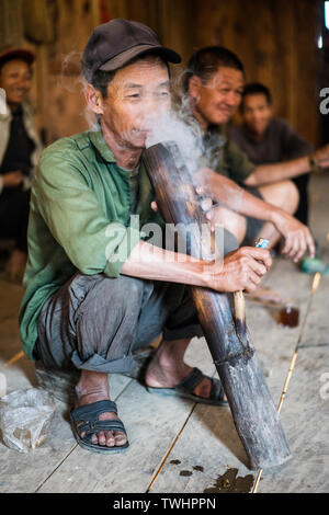 Uomo di fumare oppio dal tradizionale tubo di tabacco in akha Pixor villaggio vicino Phongsali, Laos. Foto Stock