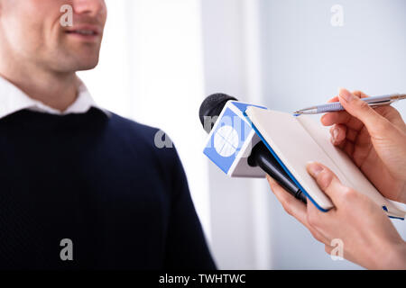 Giornalista iscritto sul diario mentre prendendo un'intervista di imprenditore Foto Stock