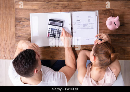 Sottolineato Coppia Giovane Guardando fattura sulla scrivania in legno Foto Stock