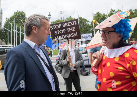 Westminster, Londra, Regno Unito. 24 maggio 2019. Il 2019 la direzione del partito conservatore elezione è stato attivato quando Theresa Maggio ha annunciato il 24 maggio 2019 che lei dovrebbe dimettersi come leader del Partito conservatore il 7 giugno e come Primo Ministro una volta un successore è stato eletto. Oggi è l'ultimo giorno di scrutinio quando gli altri candidati si sono ridotti a due. Un pro-Europa protester si veste come un clown che indossa una maschera di Boris Johnson dibattiti con un membro del pubblico. In Commons il voto è luogo per selezionare gli ultimi due candidati che l'appartenenza di partito voteranno per eleggere il leader. Foto Stock