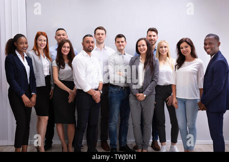 Gruppo di giovani successo multi-etnica imprenditori in piedi in ufficio guardando la fotocamera Foto Stock