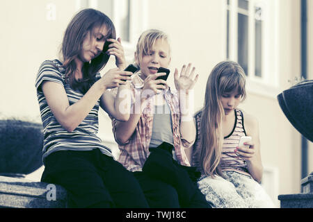 Gruppo di felice ragazze adolescenti utilizzando i telefoni intelligenti contro un edificio scolastico Foto Stock