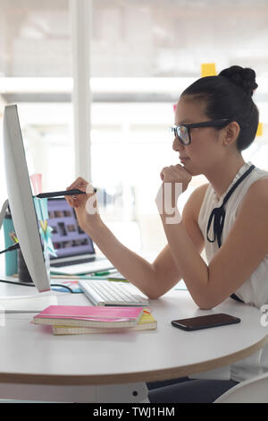 Femmina di graphic designer che lavora sul computer presso la scrivania in un ufficio moderno Foto Stock