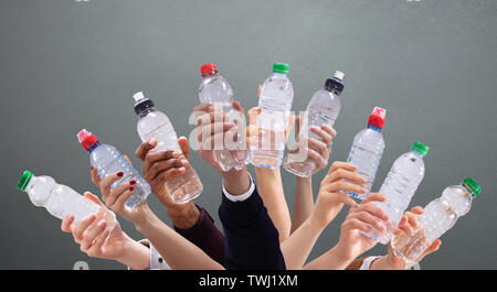 Gruppo di diverse persone che trattengono le bottiglie di acqua in una fila contro lo sfondo di colore verde Foto Stock