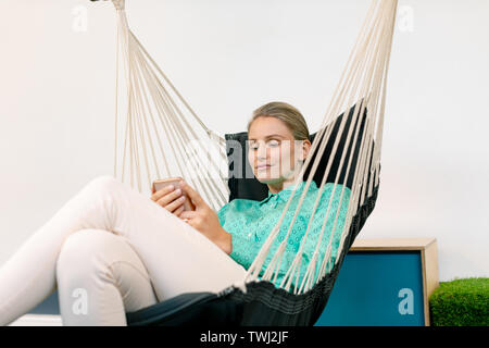 Imprenditrice utilizzando il telefono cellulare durante i momenti di relax Foto Stock