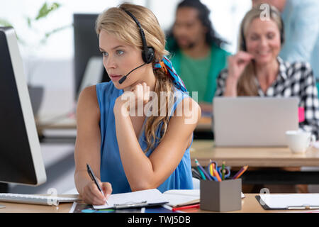 Femmina customer service executive lavorare alla scrivania in un ufficio moderno Foto Stock