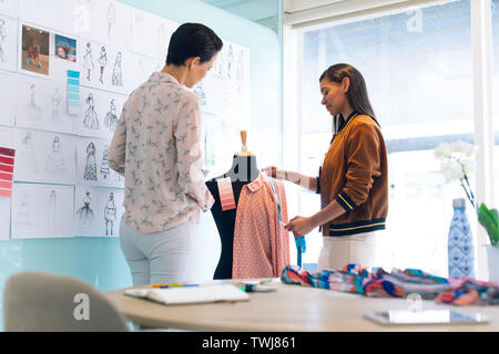 Moda femminile designer che lavorano insieme lavorando su indumento sul modello di sartoria Foto Stock