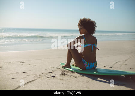 Donna rilassante sulla tavola da surf in spiaggia Foto Stock
