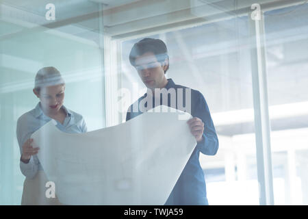 Maschio e femmina architetti discutendo su blueprint in office Foto Stock