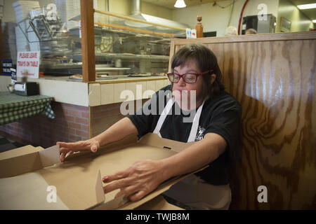 Marietta, GA, Stati Uniti d'America. 19 giugno 2019. Kathleen Gruen, 56, piega le scatole per prendere-out pizza in un piccolo ristorante italiano. Gruen, che ha la sindrome di Down, un disordine genetico, ha lavorato lo stesso supportato-occupazione lavoro per dodici anni, 2 giorni a settimana. Il lavoro aiuta a conservare la sua indipendenza, vive con due compagni di stanza in un supportati appartamento vivente. Ella ha sostegno da parte di personale addestrato e finanziato dalla sua rinuncia Medicaid. Credito: Robin Rayne/ZUMA filo/Alamy Live News Foto Stock