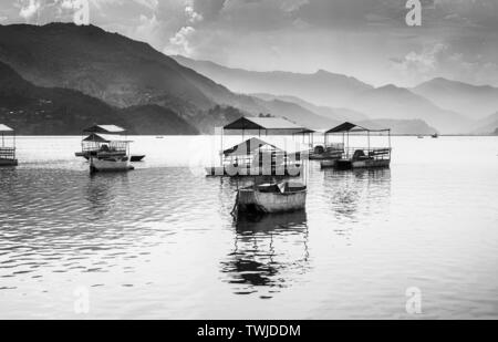 Barche a pedali parcheggiato nel lago Phewa, in bianco e nero,Tramonto nuvole sullo sfondo Pokhara Nepal. Foto Stock