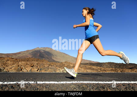 In volata esecuzione di donna - femmina runner formazione jogging all'aperto sulla strada di montagna in un paesaggio fantastico natura. Montare il bellissimo modello di fitness che lavora fuori per la maratona fuori in estate. Foto Stock