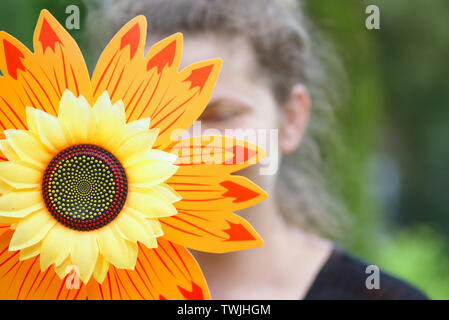 Close-up del girasole artificiale e volto femminile in backgrpind sfocata Foto Stock