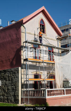 I lavoratori che operano in un cantiere a lavorare su piastrelle modernizzare la facciata di una casa in costruzione Porto Portogallo Europa KATHY DEWITT Foto Stock