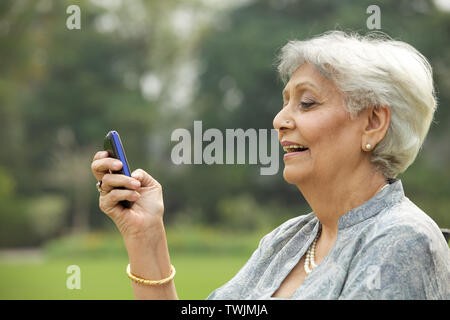 Messaggi di testo di vecchia donna e sorridente Foto Stock