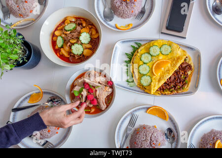 Mano a raggiungere la coppa con frittata di uova e la zuppa piccante di cibo in Asia Foto Stock