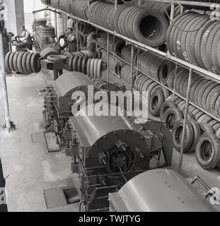 Degli anni Cinquanta, foto storiche da questa epoca che mostra la parte interna di un pneumatico di un veicolo in fabbrica, Inghilterra, Regno Unito, con la produzione di pneumatici e di macchine diverse righe di pneumatici impilati su uno scaffale. Foto Stock