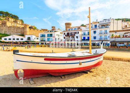 TOSSA DE MAR, Spagna - giu 3, 2019: barche da pesca sulla spiaggia di sabbia dorata in Tossa de Mar città con case colorate in background, Costa Brava, Spagna. Foto Stock