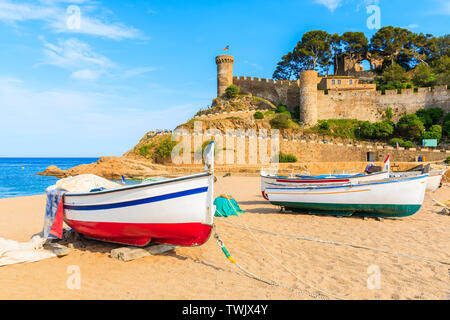 Barche di pescatori sulla spiaggia di sabbia dorata nella baia con castello in background, Tossa de Mar, Costa Brava, Spagna Foto Stock