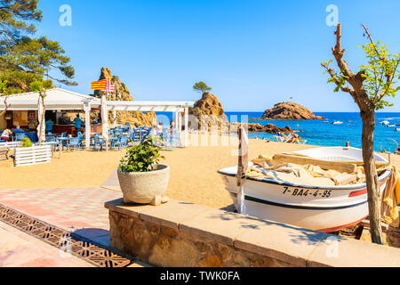 TOSSA DE MAR, Spagna - giu 3, 2019: barca da pesca e il ristorante sulla spiaggia di sabbia in Tossa de Mar città, Costa Brava, Spagna. Foto Stock