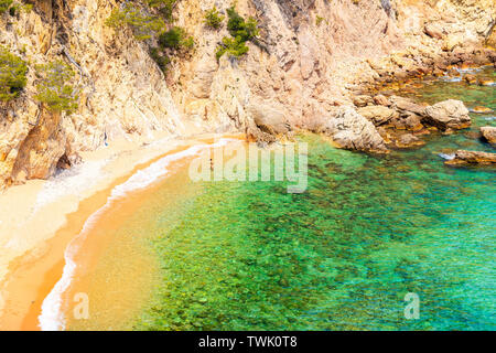 Unidentified giovane donna camminare al di fuori dell'acqua sulla spiaggia appartata vicino a Cala Giverola, Costa Brava, Spagna Foto Stock