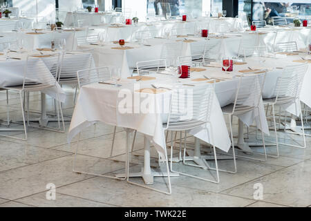 Bianco tavoli da pranzo con tovaglia e bicchiere di vino,igienico,forcella nel ristorante Foto Stock