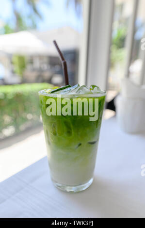 Iced tè verde Matcha con il latte con paglia in vetro su tavola Foto Stock