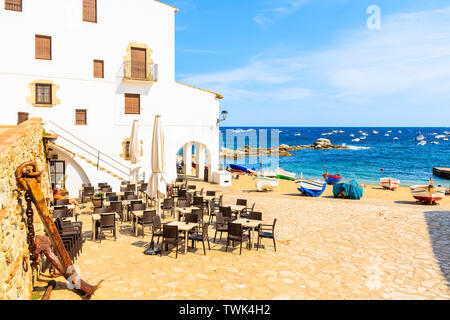 Ristorante e le tradizionali barche di pescatori sulla spiaggia di Calella de Palafrugell, scenico villaggio con case bianche e la spiaggia di sabbia chiara con acqua blu, C Foto Stock